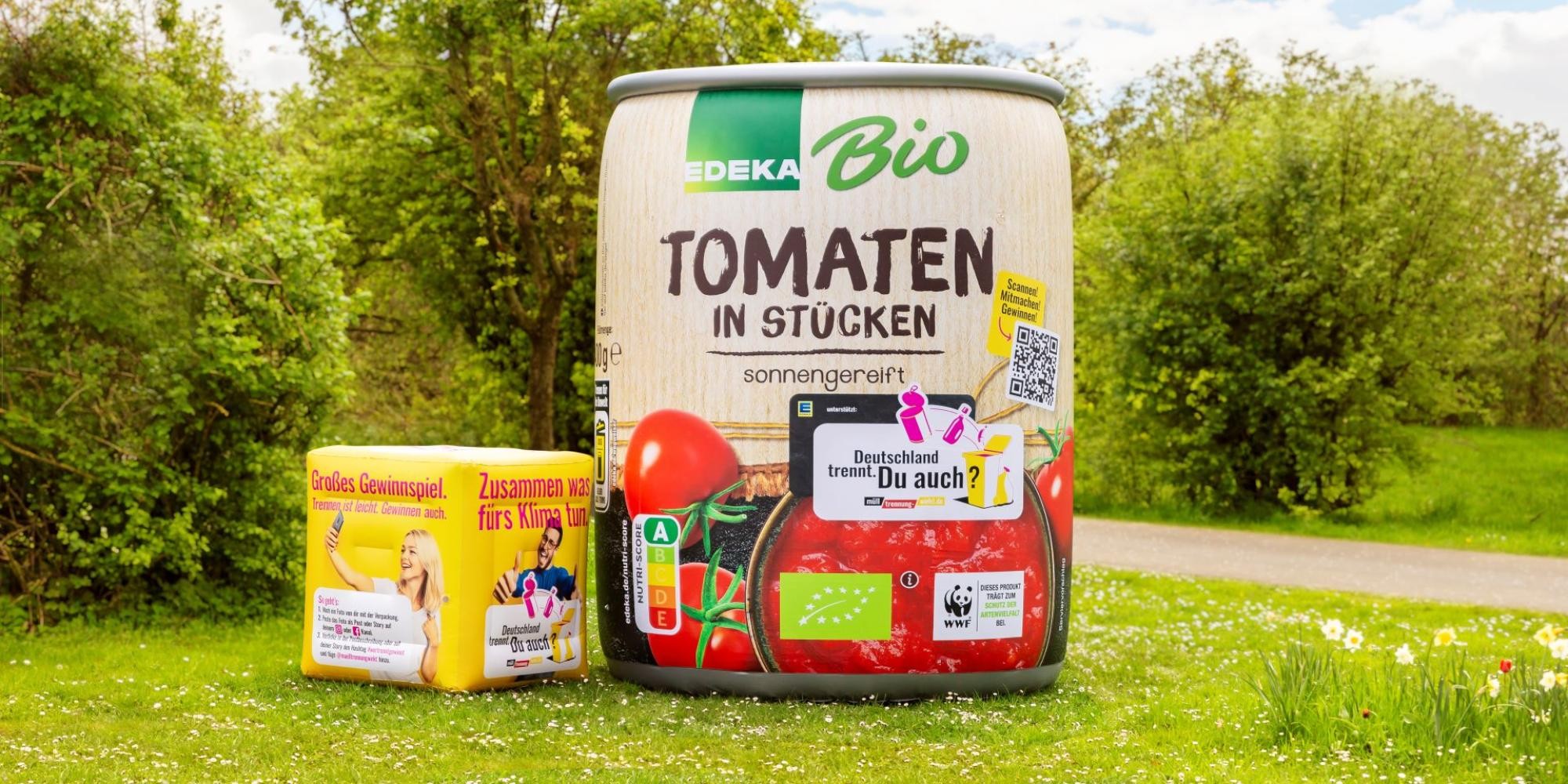 Riesige Tomatendose von EDEKA steht im Grünen