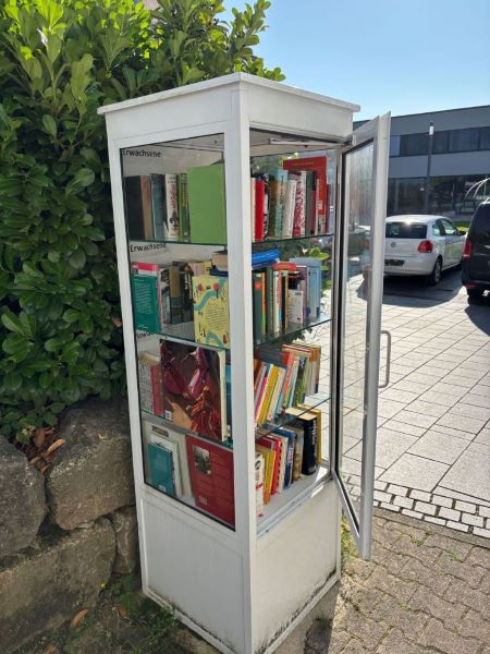 Gut gefüllter, weißer Bücherschrank mit geöffneter Tür