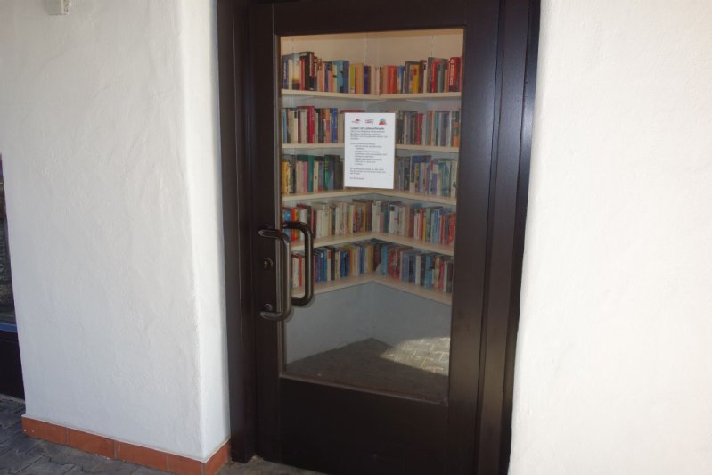 Tür mit Glasscheibe, hinter der Bücher im Regal zu sehen sind.
